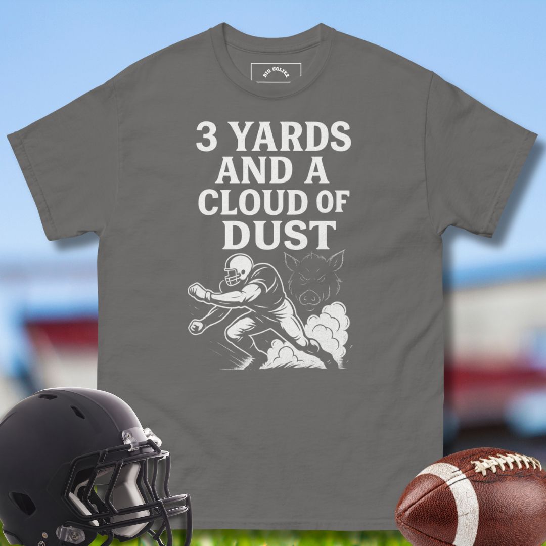 Gray -shirt with football graphic and text, helmet, and football on a sports field background with the design 3 Yards and a Cloud of Dust by Big Ugliez