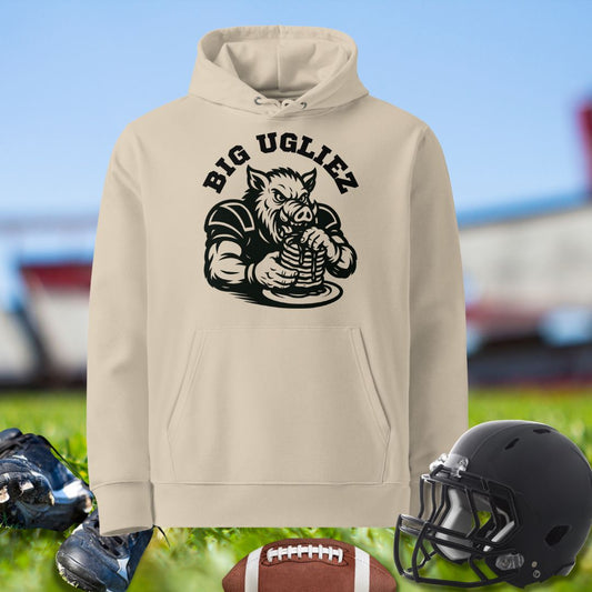 Beige hoodie with 'Big Ugliez' graphic on a sports field background. Hoodie for Olinemen football players.