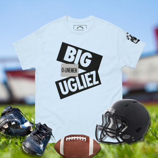 Light blue t-shirt with 'BIG UGLIEZ' text, football helmet, cleats, and football on grass.