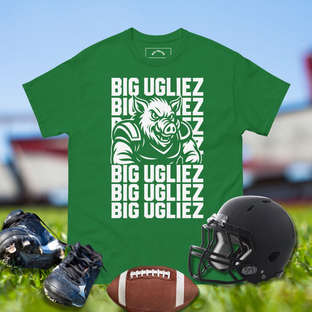 Green t-shirt with 'BIG UGLIEZ' text and pig graphic, surrounded by football gear on grass.