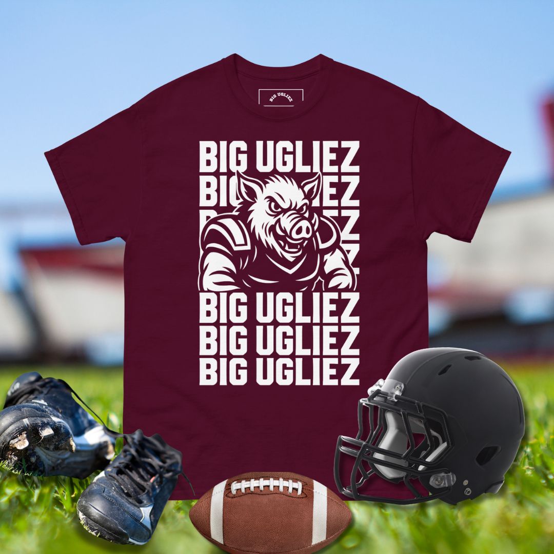 Maroon t-shirt with 'BIG UGLIEZ' graphic, football, helmet, and shoes on a sports field background