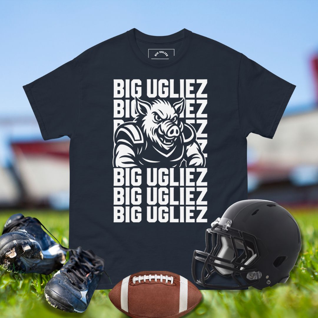 Black t-shirt with 'BIG UGLIEZ' graphic, football, helmet, and shoes on grass