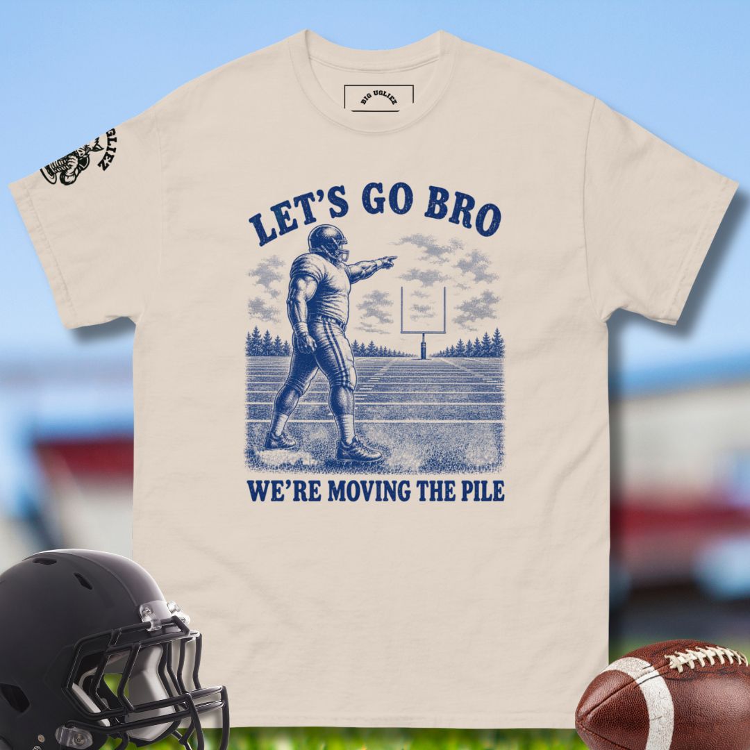Beige t-shirt with football graphic and text 'Let's Go Bro, We're Moving the Pile' on a blurred sports field background.