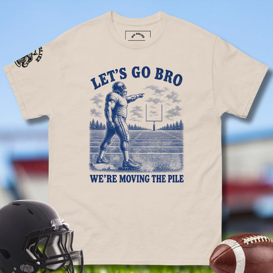 Beige t-shirt with football graphic and text 'Let's Go Bro, We're Moving the Pile' on a blurred sports field background.