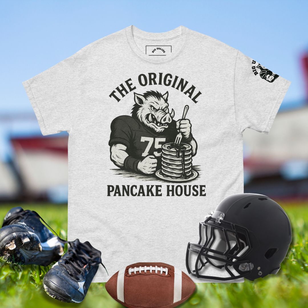 Gray t-shirt with 'The Original Pancake House' graphic, football, helmet, and cleats on grass.