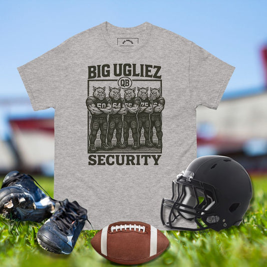 Gray t-shirt with 'BIG UGLIEZ SECURITY' graphic, football, helmet, and cleats on grass.