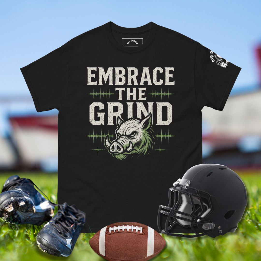 Vintage-style Big Ugliez Embrace the Grind tee featuring bold distressed typography and hog mascot accent in white and neon green for O-linemen and football players.