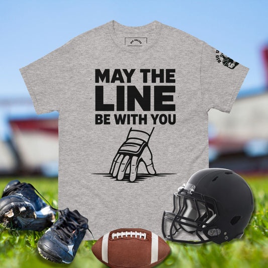 Football lineman hand in 3-point stance with taped wrist and glove under bold text May the Line Be With You in gray tshirt