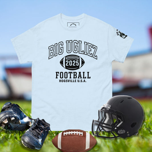 White t-shirt with 'BIG UGLIEZ 2025 FOOTBALL HOGSVILLE U.S.A.' text, black football helmet, cleats, and football on grass.
