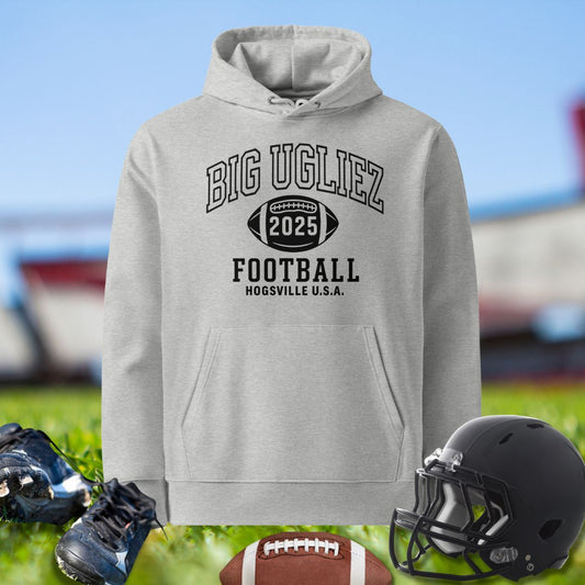 Gray hoodie with 'BIG UGLIEZ 2025 FOOTBALL' text, football, helmet, and shoes on grass.