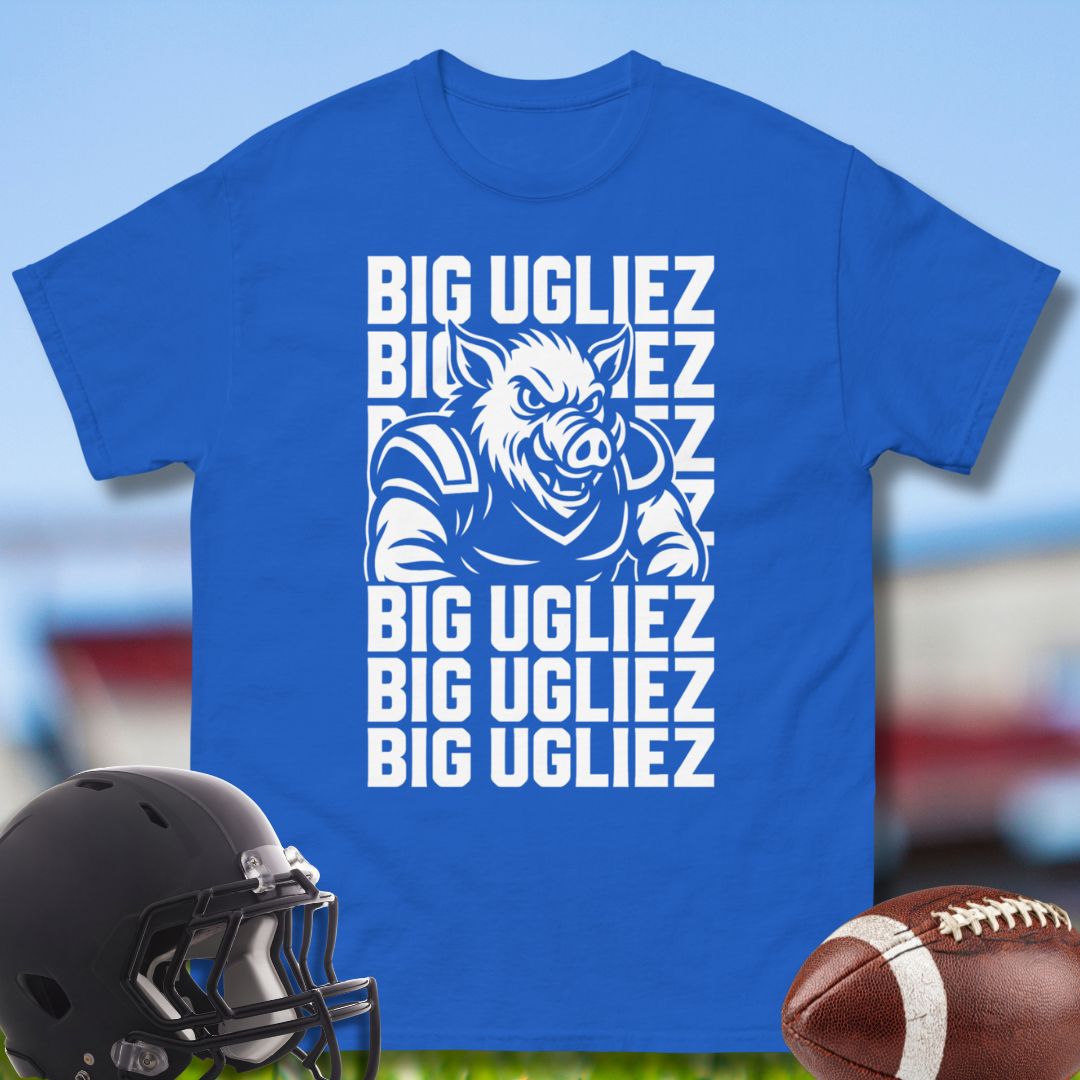 Blue t-shirt with a graphic and text 'BIG UGLIEZ' on a blurred sports equipment background