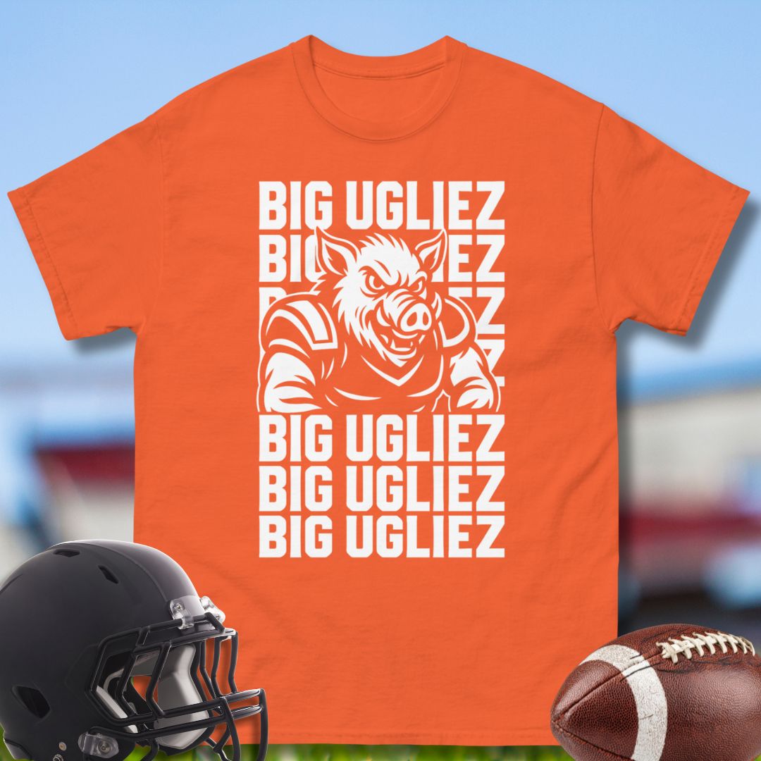 Orange t-shirt with graphic design and text, helmet, and football on a blurred sports field background