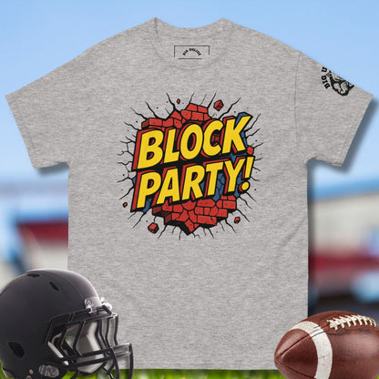 Gray t-shirt with 'Block Party!' design, football helmet, and football on a blurred sports field background. By Big Ugliez O-line brand
