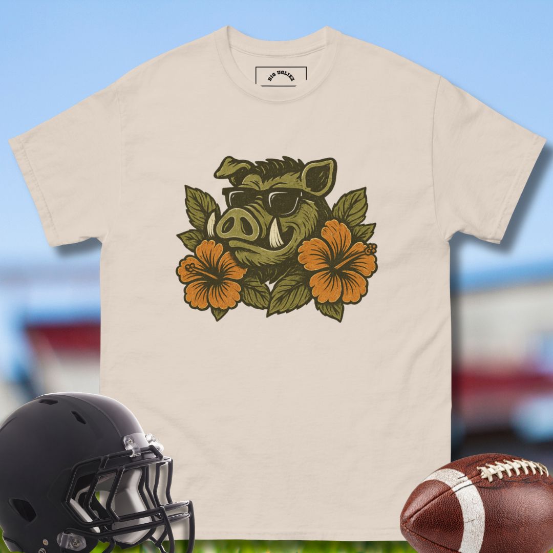 Beige t-shirt with a boar and floral design, black helmet, and football on a blurred sports field background.