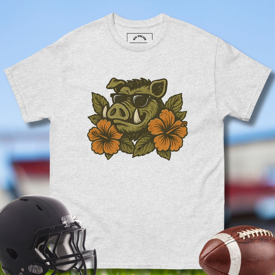 Gray t-shirt with a boar and floral design, helmet, and football on a blurred background