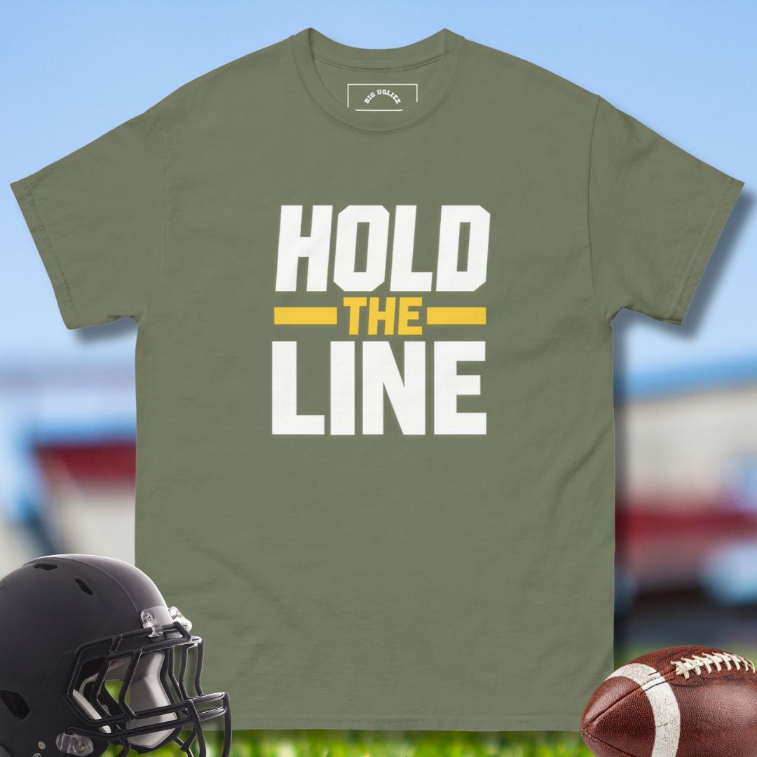 Green t-shirt with 'Hold the Line' text, black football helmet, and brown football on a blurred sports field background.