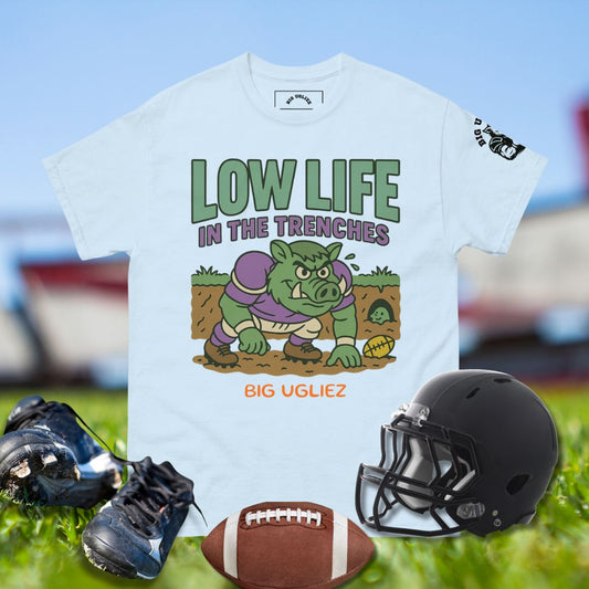 T-shirt with 'Low Life in the Trenches' graphic, football, helmet, and cleats on a sports field background