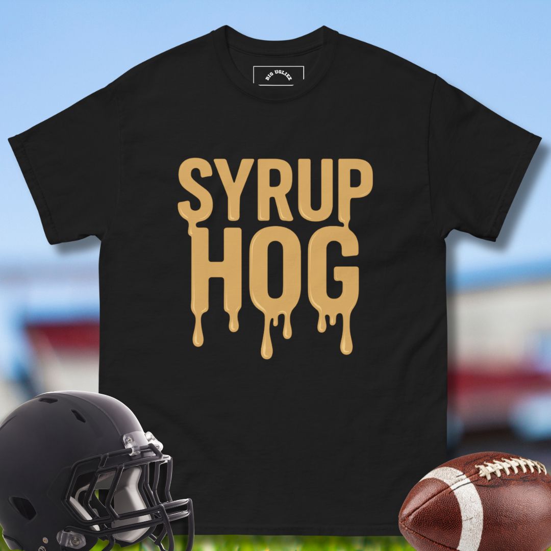 Black t-shirt with 'Syrup Hog' text, football helmet, and football on a blurred sports field background.