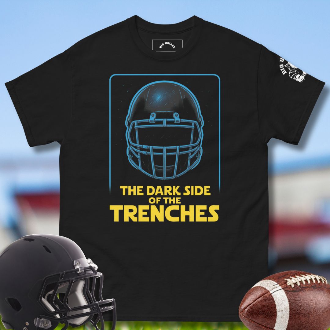 The Dark Side of the Trenches  Black t-shirt with football helmet graphic and text, helmet and football on a sports field background