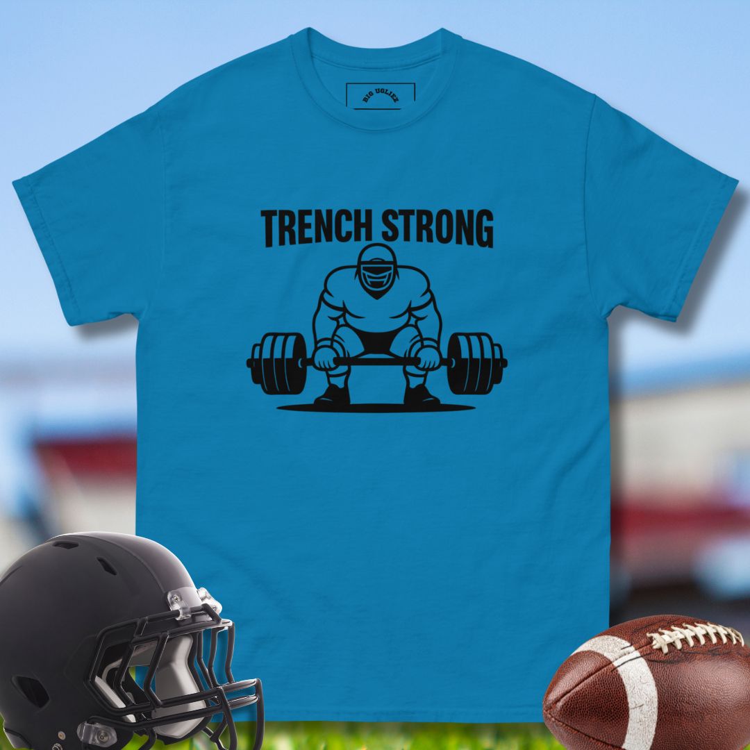 Blue t-shirt with 'Trench Strong' graphic and football helmet and ball on grass background