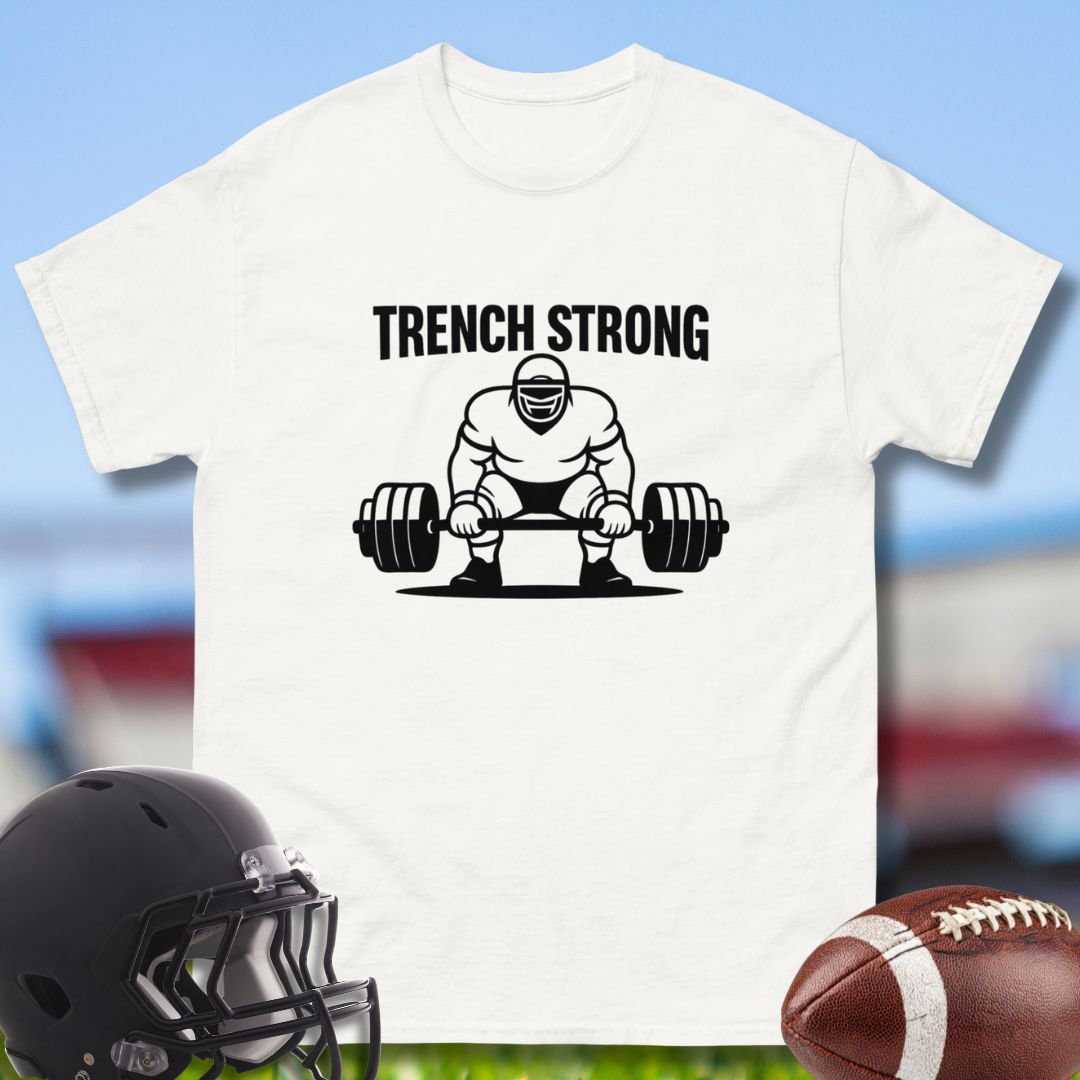 White t-shirt with 'Trench Strong' graphic featuring a person lifting weights, helmet, and football on a sports field background.
