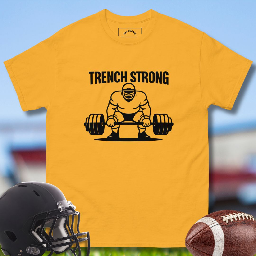 Yellow t-shirt with 'Trench Strong' graphic featuring a person lifting weights, helmet, and football on a sports field background.