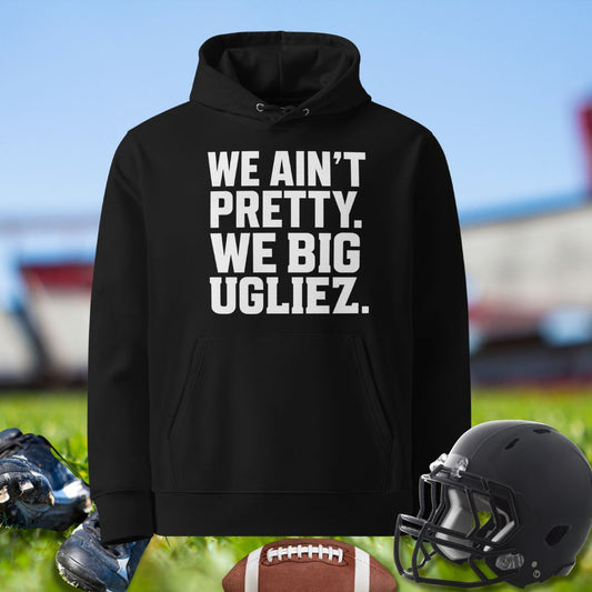 Black hoodie with text 'WE AIN'T PRETTY, WE BIG UGLIEZ' on a sports field background for the Olineman by Big Ugliez.