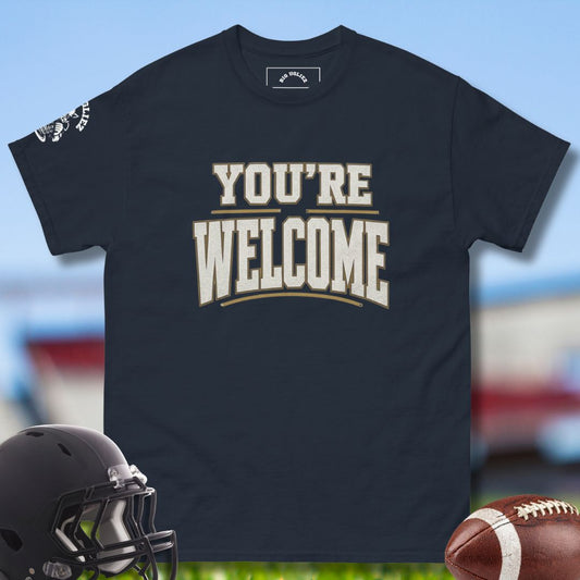 Black t-shirt with 'YOU'RE WELCOME' text, football, and helmet on a sports field background