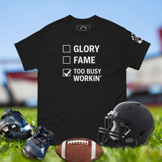 Black t-shirt with motivational text, football, helmet, and shoes on grass