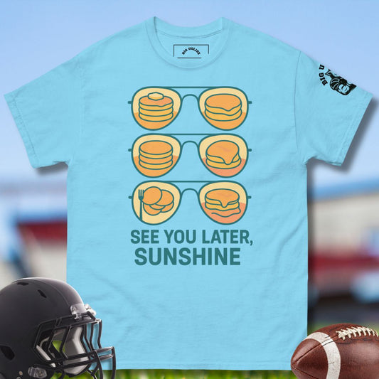 Light blue t-shirt with cheeseburger sunglasses graphic and 'See You Later, Sunshine' text, displayed with a football and helmet.